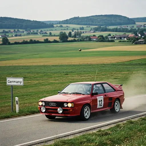 A vintage Audi Sport Quattro driving on a rural road in Germany, with rolling hills in the background.