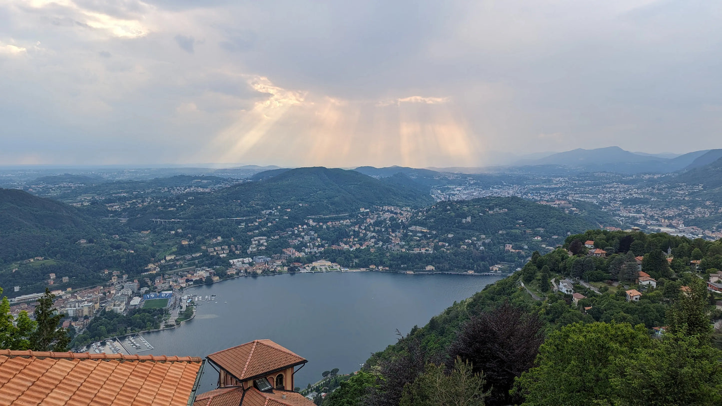 Scenic landscape of Lake Como in Italy's Lombardy region, under a moody, cloudy sky.