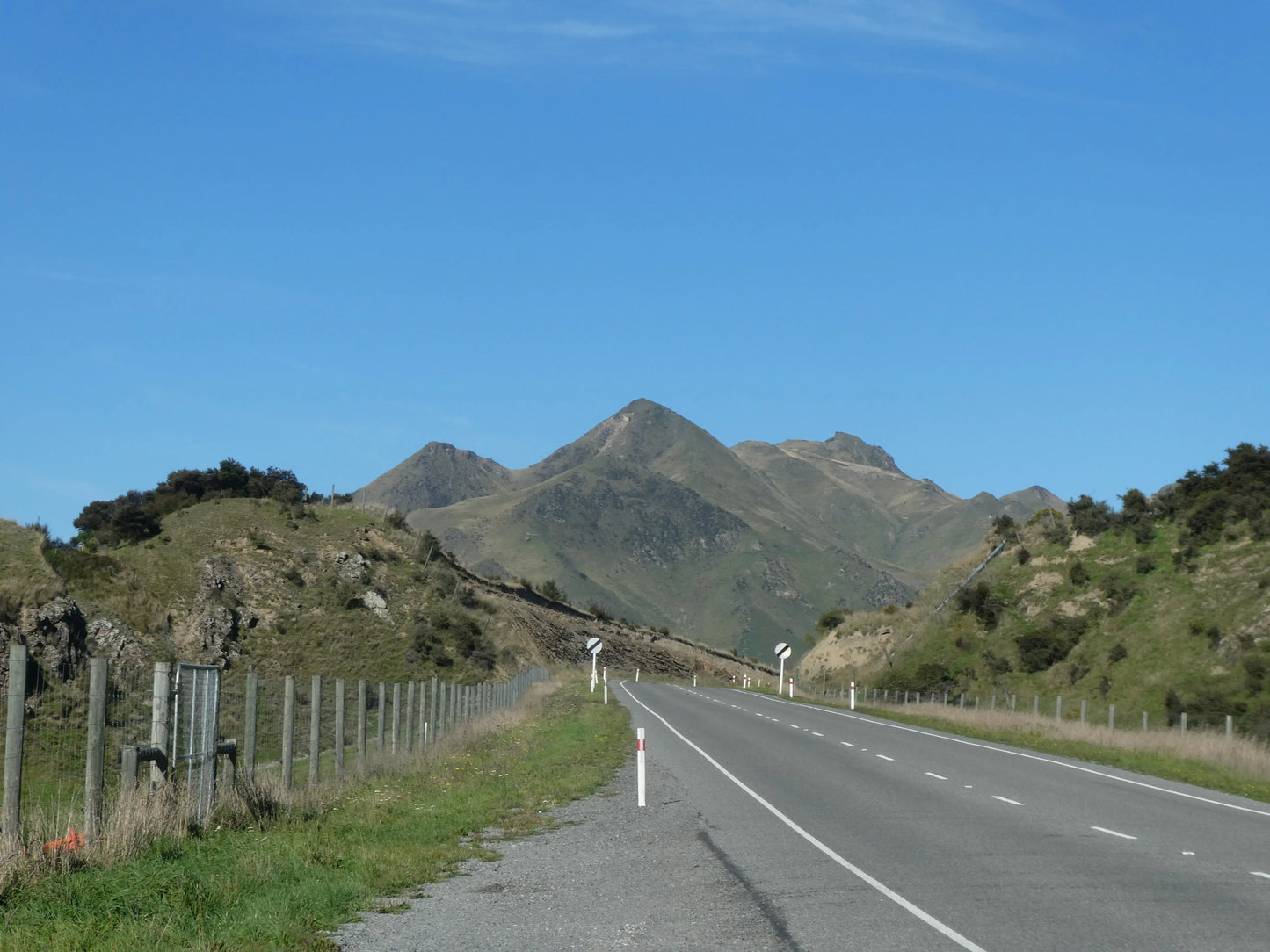 Driving through the dramatic tussock landscape of Lindis Pass, New Zealand.